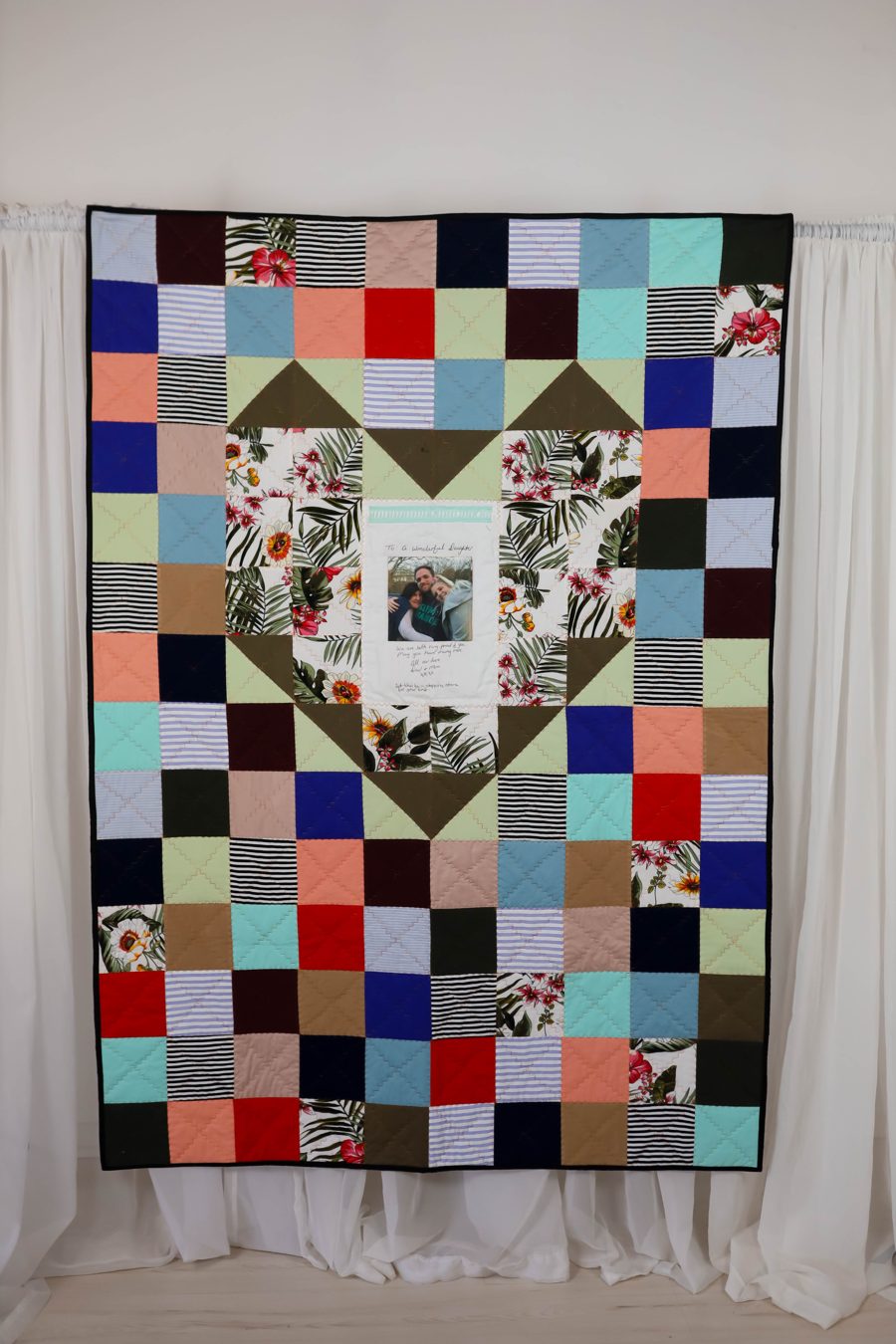 Memory quilt made from a mother's clothes, with a heart of tropical fabric and a framed photo in the middle