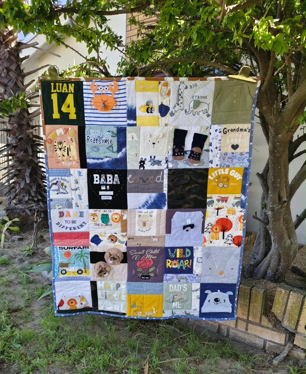 Memory quilt made from a little boy's baby clothes, hanging on a tree